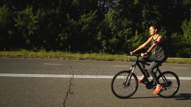 Una mujer monta una bicicleta en el camino — Vídeo de stock