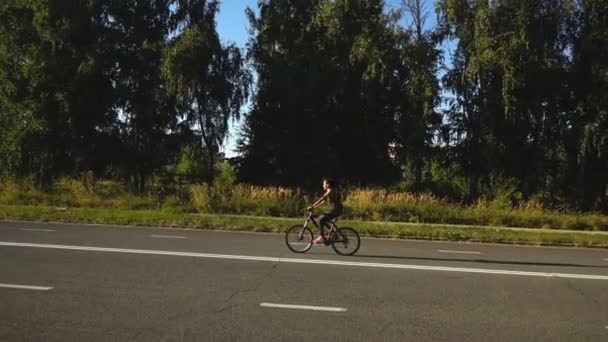 Женщина катается одна на велосипеде в сельской местности, проводит свои активные летние выходные — стоковое видео