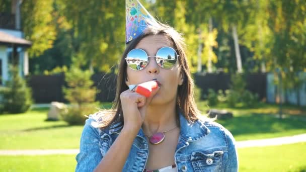 Adolescente ragazza in cappello festa soffiando in corno partito — Video Stock
