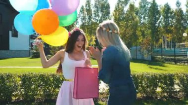 sarışın ve esmer genç kadınlarda doğum günü şapkalı renkli elbise. Sarılma arkadaşlar