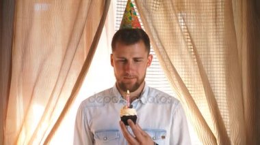 parti şapkalı bir adam cupcake mum dışarı havaya uçurur