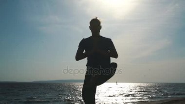 Sunset Beach yoga yaparken genç adam silüeti