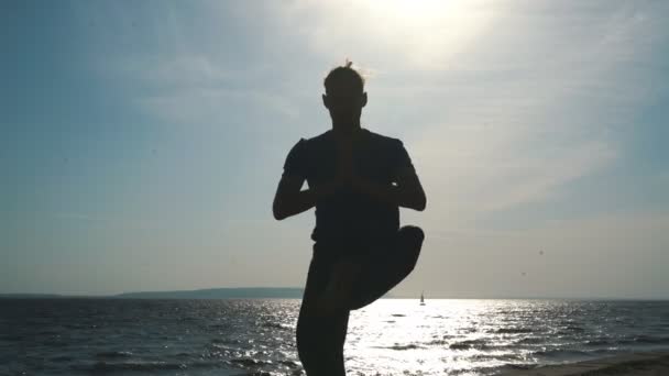 Silhouet van jonge man doen yoga in sunset beach — Stockvideo