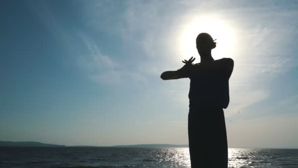 Man silhuetten gör yoga övning på sunset beach — Stockvideo