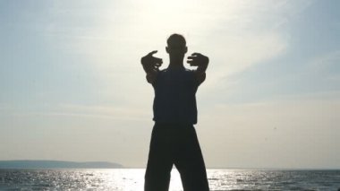 Sunset Beach yoga yaparken genç adam silüeti