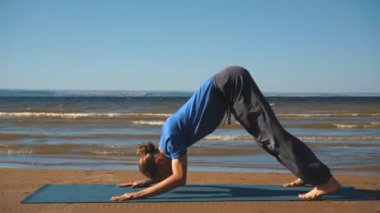 Yoga ln plaj pratik bir genç adam. Yukarı köpek bakacak şekilde