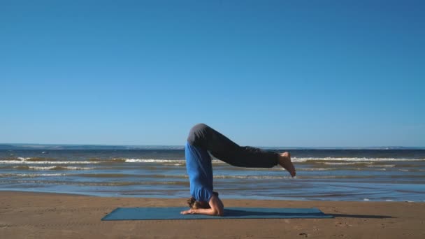 Homem forte praticando pose de ioga difícil na praia — Vídeo de Stock