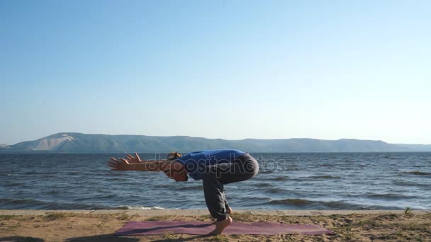 Ung man öva yoga på kusten — Stockvideo