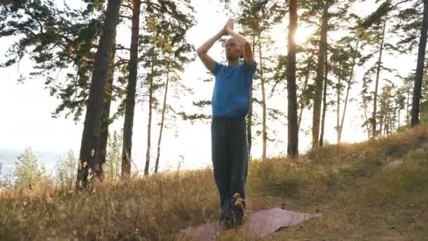 Jeune homme fait sa pratique du yoga dans le bois au coucher du soleil — Video