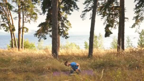 ハンサムな若い男の中に瞑想や川によって森の中で屋外のヨガ運動を行う — ストック動画