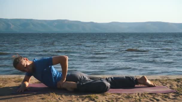 Jeune homme pratiquant le yoga sur la côte — Video