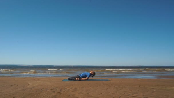 Fuerte hombre practicando difícil yoga pose en la playa — Vídeos de Stock