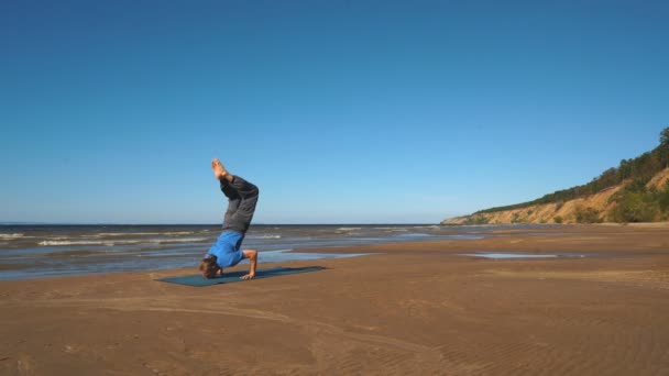 Postura del yoga del handstand por el hombre en la playa cerca del océano — Vídeos de Stock