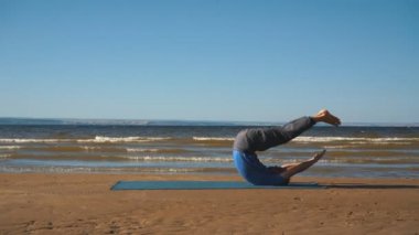 Bir kayaya günbatımı ışıkta göğüs germe yapan genç erkek