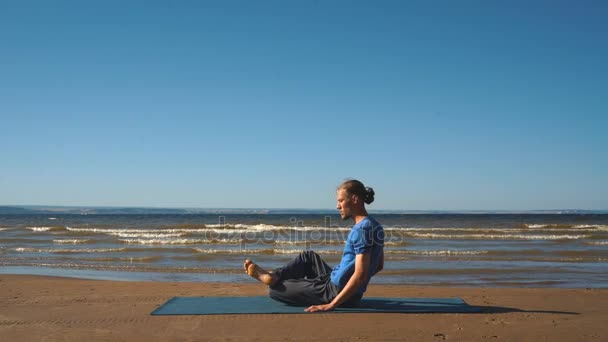 Giovane che fa stretching toracico su una spiaggia alla luce del tramonto — Video Stock