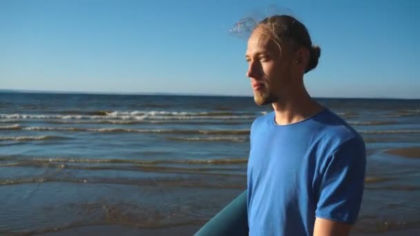 Un hombre con un rollos de yoga caminando por la playa — Vídeos de Stock