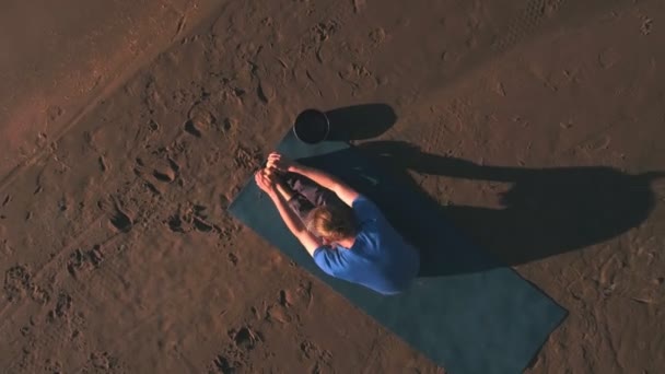 Vista aérea de un hombre hace yoga en la playa al atardecer — Vídeos de Stock