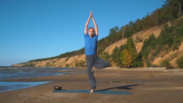 Young man doing thoracic stretching on a beach at sunset light — Stock Video