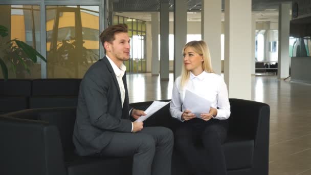 Zakenman en zakenvrouw bespreken businessplannen in de lobby van het Bureau op de Bank — Stockvideo