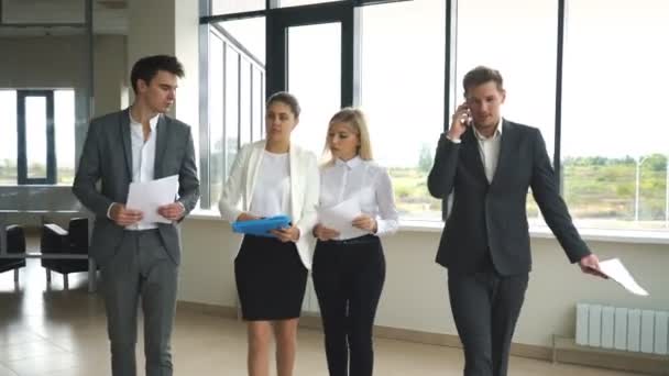 Cuatro personas de negocios hablando y caminando en el vestíbulo de la oficina — Vídeo de stock