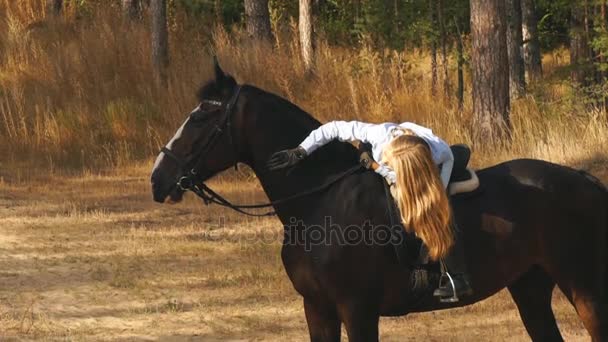 Hermosa chica montando en un caballo abrazándola y acariciando — Vídeos de Stock