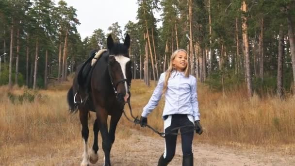 Das kleine Mädchen geht mit dem Pferd durch den herbstlichen Wald — Stockvideo