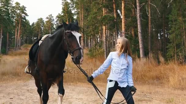 Den lilla flickan promenader i höst skog tillsammans med häst — Stockvideo