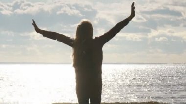 Sahilde kız kollarını gökyüzüne yükseltir