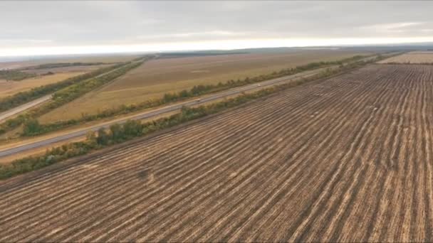 View over the early autumn fields and a dual carriageway road from the air — Stock Video