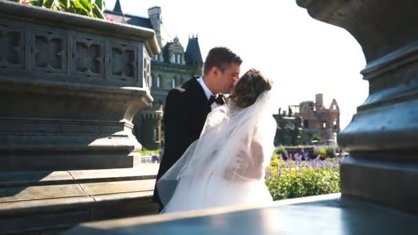 A noiva eo noivo beijando na frente de um castelo antigo — Vídeo de Stock