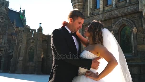 Hermoso novio romántico y hermosa novia rubia posando cerca del viejo castillo de pared — Vídeos de Stock