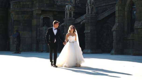 Bonito casal recém-casado feliz se divertindo perto da parede do castelo velho — Vídeo de Stock