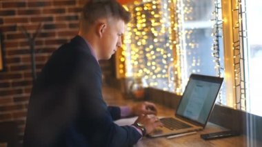 a young businessman works in a cafe and looks at the smartphone