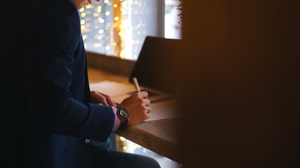 Un joven empresario se sienta en una cafetería y estudia el contrato — Vídeo de stock