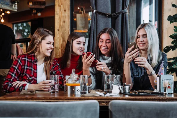 Quatre amis regardent le téléphone et rient — Photo