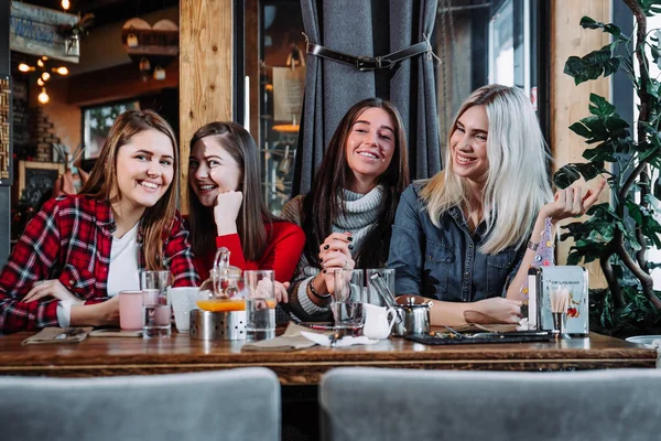 Fyra vänner i café titta på kameran och skratt — Stockfoto