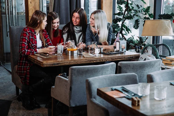 Fyra kvinnliga vänner njuter i pratar på café — Stockfoto