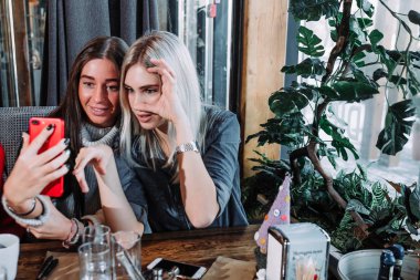 Bir kafede yemek ve selfie yapıyor iki kız