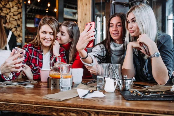 Fyra vänner sitter i tabellen i café och göra selfie på smartphone — Stockfoto