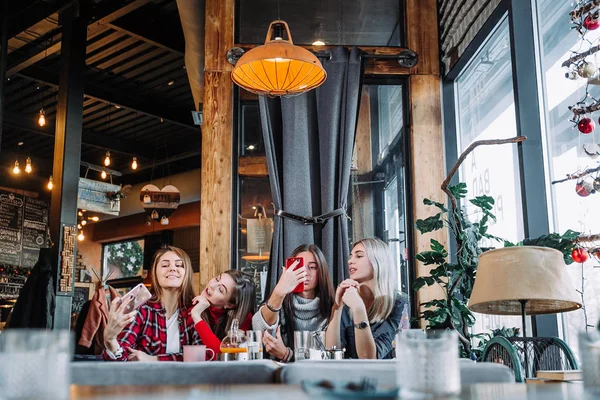 Quatre amis assis à la table dans un café et faisant du selfie sur smartphone — Photo