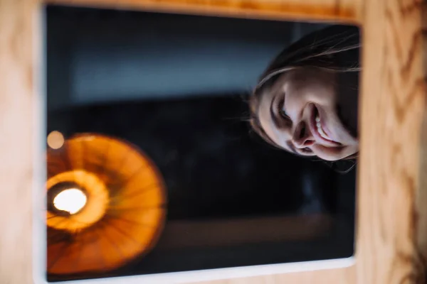 The girl smiles,the reflection in the tablet — Stock Photo, Image