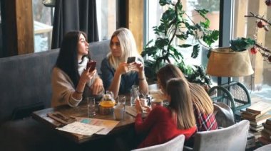 Dört kadın sosyal ağ oynarken app smartphone kullanarak kafede. Teknoloji yalıtım