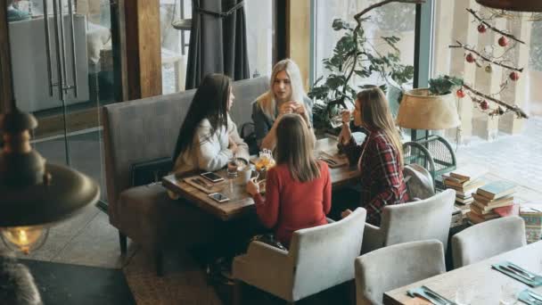 Amigos de la compañía sentados en un café en el desayuno y discutir planes — Vídeos de Stock