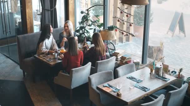 Четыре улыбающихся друга сидят в кафе и проводят время вместе — стоковое видео