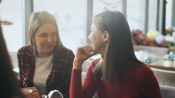 Duas mulheres bonitas bebendo café e conversando no café — Vídeo de Stock