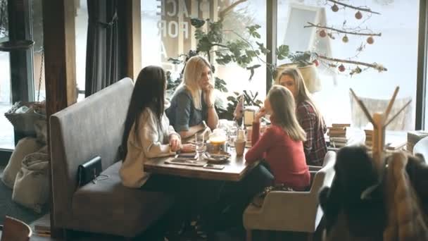 Grup dört genç insan Restoran masada oturma ve yemek sırasında eğlenmek. — Stok video