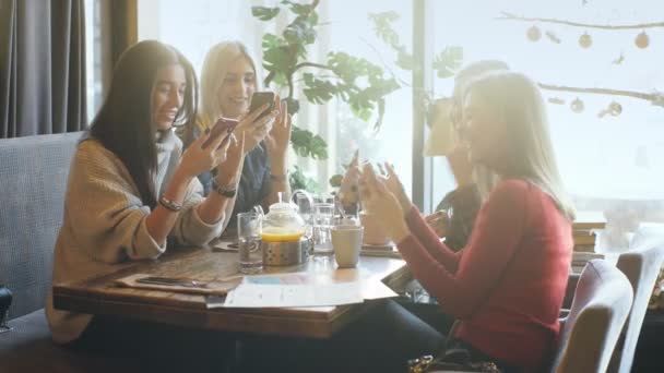 Jonge vrouw delen iets op haar mobiele telefoon met drie aantrekkelijke lachen vriendinnen — Stockvideo