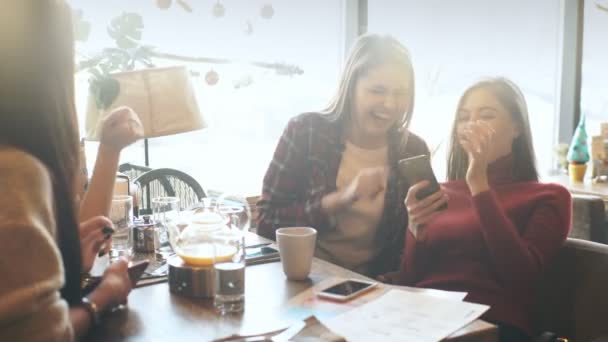 Fiatal nő cserépdarab valami-ra a mobiltelefon, három barátokkal vonzó nevető lány — Stock videók