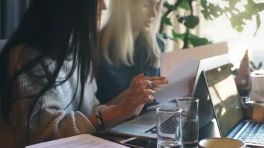 iki iş kadınları aktif bir kafede bir dizüstü bilgisayar üzerinde çalışan ve iş tartışıyor