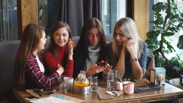 Четверо друзей смотрят в телефон и смеются — стоковое видео